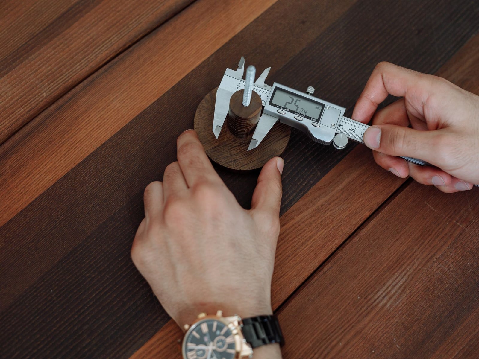 Präzise Messung eines gravierten Holzteils mit einem digitalen Messschieber